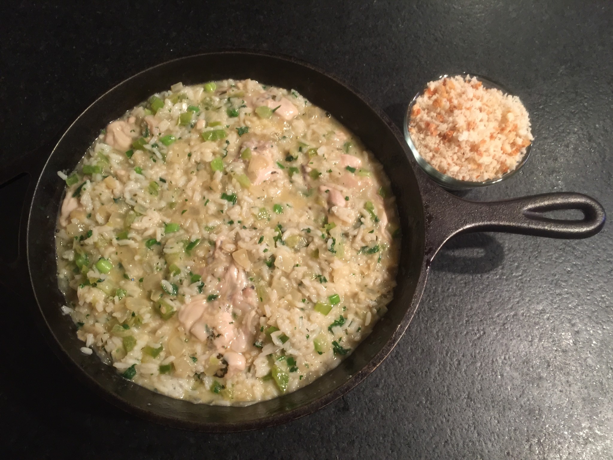 Deep skillet filled with oyster, rice and trinity mixture, ready for breadcrumb topping.